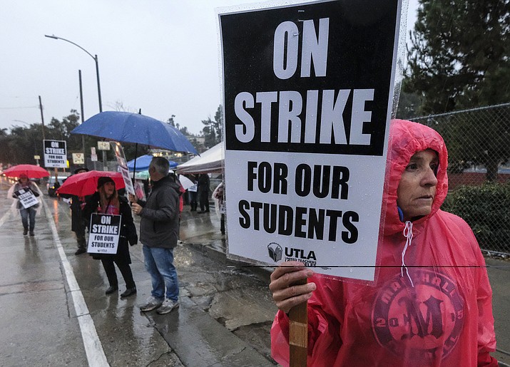 Teacher Orquidea Laqrador holds a sign strikes in the rain outside John Marshall High School, Monday, Jan. 14, 2019, in Los Angeles. Tens of thousands of Los Angeles teachers are striking after contentious contract negotiations failed in the nation's second-largest school district.(AP Photo/Ringo H.W. Chiu)