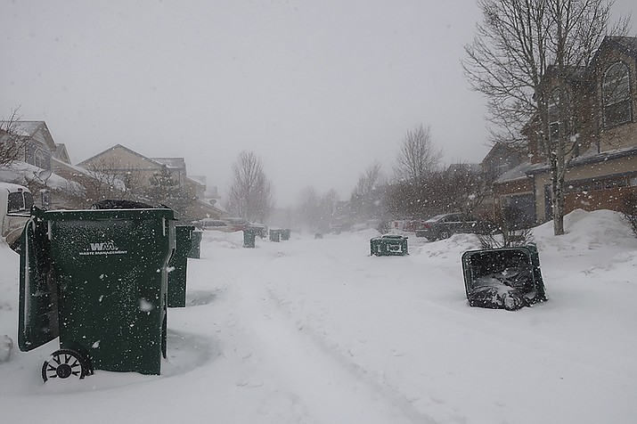 Strong wind gusts blew over trash cans in a neighborhood west of Flagstaff, Ariz., on Wednesday, Feb. 22, 2023. The storm forced closures of schools and government offices in northern Arizona, and a more than 200-mile stretch of Interstate 40. (AP Photo/Felicia Fonseca)