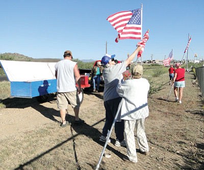 Chris Shackelford helps Lynn Hummel unfurl and raise a flag to help set up the Avenue of Flags.<br>
Courtesy photo