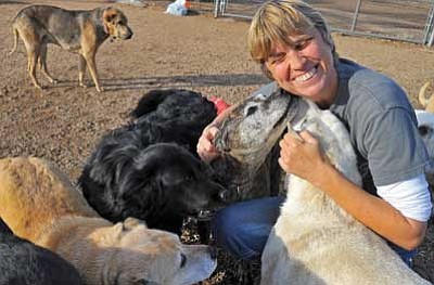 Matt Hinshaw/The Daily Courier<br>
Liz Stegmeir, a Dog Care Taker for the Circle L Ranch, takes a moment out of her busy workday to give some dogs a little affection Thursday afternoon at the ranch in Coyote Springs. The 40-acre animal sanctuary is seeking donations to keep the facility afloat.