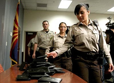 Ross D. Franklin/The Associated Press<br>
Ninety-two Maricopa County Sheriff’s Office immigration jail officers, who lost their federal power to check whether inmates are in the country illegally, turn in their credentials Wednesday in Phoenix.  
