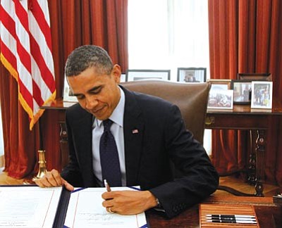 Haraz N. Ghanbari/The Associated Press<br>
President Barack Obama signs the payroll tax cut extension Friday in the White House Oval Office.