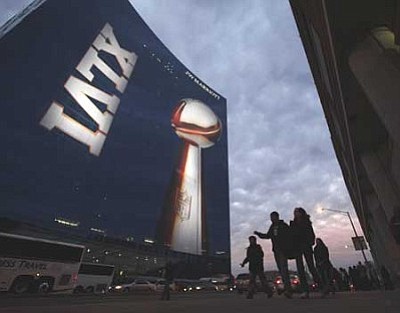 People walk past a hotel with displaying a likeness of the Vince Lombardi Trophy on Friday, Feb. 3, 2012, in Indianapolis. The New England Patriots are scheduled to face the New York Giants in NFL football's Super Bowl XLVI on Feb. 5. (AP Photo/Charlie Riedel)