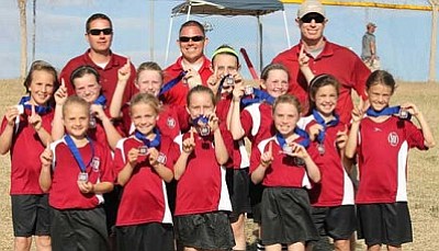 The Prescott Pride Girls AYSO U10 Tournament Team holds up their championship medals from the Crossroads Cup.