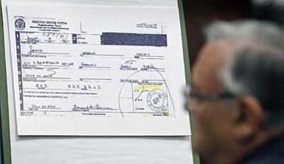 The Associated Press/Ralph Freso<br>
Maricopa County Sheriff Joe Arpaio looks at a copy of President Obama’s selective service card during a news conference Thursday in Phoenix. 

