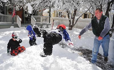Les Stukenberg/The Daily Courier<br>
Travis Newby tosses next door neighbor Cash Scarpignato into a snow bank on Monday. Most area schools were closed because of the storm.