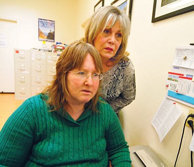 Les Stukenberg/The Daily Courier<br>
Gail Kenny, left, and Liz Toone, study a computer image at New Horizons in Prescott Valley. Kenny, who helps people access to their available benefits, will be one of 500 people nationwide who will lose their jobs if Congress does not reauthorize the spending that pays for their positions.
