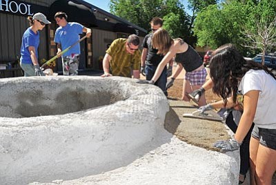 Matt Hinshaw/The Daily Courier<br>
Kristin Anthony, left, creator of the Granite Creek Park bench, helps Kestrel High School 
creative arts teacher Ron Harvey and his students put a coat of concrete on a replacement bench built on the high school’s property in Prescott Thursday morning.
