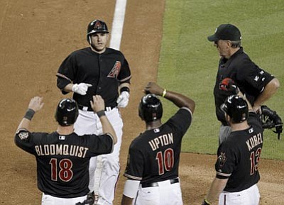 Arizona Diamondbacks' Miguel Montero, top left, is greeted at home plate by teammates Willie Bloomquist (18), Justin Upton (10) and Jason Kubel (13) after Montero's grand slam against the Oakland Athletics, as home plate umpire Tim McClelland watches during the fifth inning in an interleague baseball game Saturday, June 9, 2012, in Phoenix. (AP Photo/Ross D. Franklin)