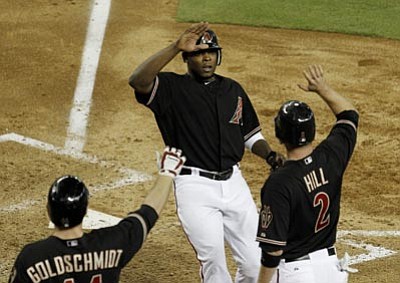 Arizona Diamondbacks' Justin Upton, top, gets high-fives from teammates Aaron Hill (2) and Paul Goldschmidt after scoring against the Chicago Cubs during the fourth inning of a baseball game Saturday, June 23, 2012, in Phoenix. (AP Photo/Ross D. Franklin)