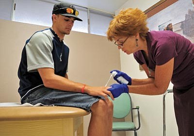 Matt Hinshaw/The Daily Courier<br>Rebecca Oldani, a board-certified nurse practitioner, treats Tyler Wickham’s hand Thursday afternoon at the Prescott Health Clinic. The clinic offers low-cost health services and does not take insurance.