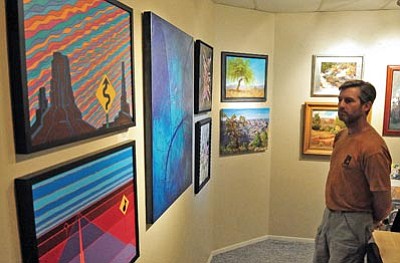 Matt Hinshaw/The Daily Courier<br>Above, John Neeley, who’s visiting Prescott from Kansas City, Mo., admires paintings inside the Mountain Artists Gallery during the 5th annual Prescott Area Artists’ Studio Tour. Below, artist Bonnie Casey works on a landscape painting inspired by Flagstaff’s fall colors.