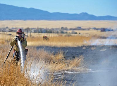 Matt Hinshaw/The Daily Courier<br>A Central Yavapai Fire District firefighter extinguishes part of a 4-acre brush fire in Coyote Springs near the intersection of Turtle Rock Road and Orion Way Wednesday afternoon in Prescott Valley. The fire was started by sparks from someone welding outside of their home.