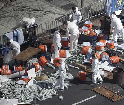 The Associated Press<br>
Investigators comb through the post finish line area of the Boston Marathon at Boylston Street, two days after two bombs exploded just before the finish line.