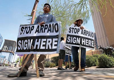 Matt York/The Associated Press<br>
Simon Lopez, left, and Hiliaro Islas hold signs while trying to collect signatures in an effort to recall Maricopa County Sheriff Joe Arpaio Wednesday. 

