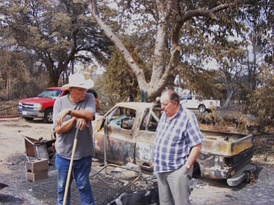 Courtesy photo<br>
Richard Mayer, a former Yavapai County sheriff’s deputy who worked the Yarnell area prior to his retirement, sifts through the ashes at his former homesite as he discusses the town’s situation with Paul Chastain. He lost everything in the wildfire, but fortunately, he has insurance coverage.    

