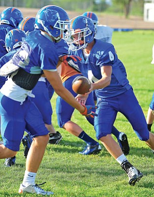 Matt Hinshaw/The Daily Courier<br>Chino Valley quarterback Jake Clawson hands the ball off to Brandon Lasky (23) while running a play during team practice on Aug. 9 in Chino Valley.