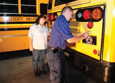 Les Stukenberg/The Daily Courier<br>
Prescott Fire Wildland Division Chief Darrell Willis puts the first Granite Mountain Hotshots plate on a Prescott Unified School bus as Director of Transportation Nora Frye looks on, Monday morning in Prescott.