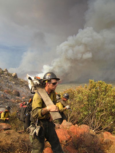 Courtesy photo<br>
Granite Mountain Hotshot Andrew Ashcraft carries his chainsaw and walks in front of the camera as fire and smoke from the Yarnell Hill Fire moves across the terrain below them at 3:52 on the afternoon of June 30, 2013. Photo recovered from a Granite Mountain Hotshots’ personal camera following the horrific Yarnell Hill Fire that killed 19 of the Granite Mountain Hotshots on June 30, 2013.