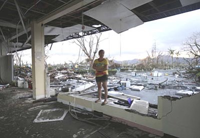 Bullit Marquez/The Associated Press<br>
A woman stands amidst the devastation brought about by powerful Typhoon Haiyan at Tacloban city, in Leyte province, central Philippines, Saturday.