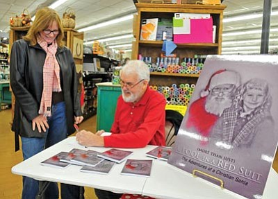 Matt Hinshaw/The Daily Courier<br>Clay Conboy signs a copy of his book “A Fool in a Red Suit.”