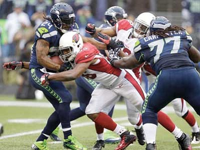 Elaine Thompson/The Associated Press<br>
Seattle Seahawks running back Marshawn Lynch, left, is tackled by Arizona Cardinals tight end Jake Ballard as Seahawks’ James Carpenter stands near, in their  game Sunday in Seattle.