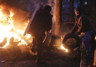 Efrem Lukatsky/The Associated Press<br>
Activists burn tires at barricades close to Independence Square, the epicenter of the country's current unrest, in Kiev, Ukraine, Thursday, as, according to the protesters, the resulting heavy black smoke does not  allow riot police snipers to aim easily at protesters.