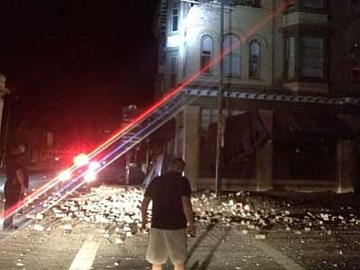 Damage to a building in Napa, California, is surveyed early this morning. Officials say an earthquake with a preliminary magnitude of 6.0 has been reported in California's northern San Francisco Bay area. (AP Photo/Lyall Davenport)