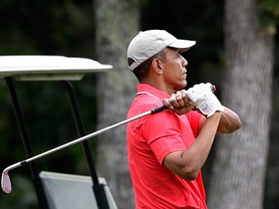 President Barack Obama follows through on a swing while golfing at Farm Neck Golf Club, in Oak Bluffs, Mass., on the island of Martha's Vineyard, on Aug. 23, 2014. (Associated Press Photo/Steven Senne)