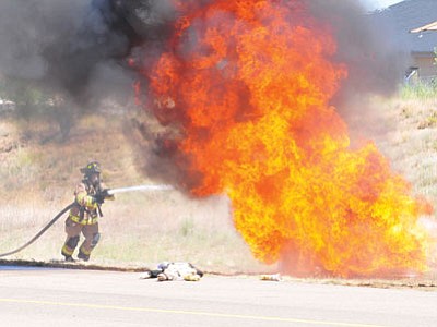 A Prescott firefighter sprays down one of the burn barrels during a mass casualty drill involving two downed aircraft, a live fire and 25 patients who need to be treated Aug. 16, 2011, at Ernest A. Love Field in Prescott. A similar drill will take place Saturday at the airport. (The Daily Courier, file photo)