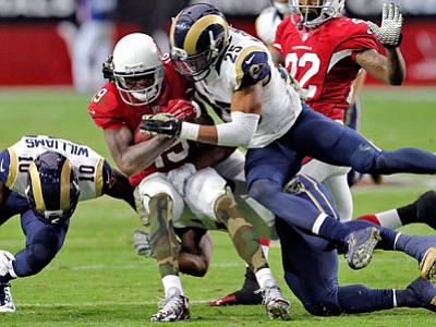 Arizona Cardinals wide receiver Ted Ginn (19) is hit by St. Louis Rams strong safety T.J. McDonald (25) during the first half of Sunday’s game in Glendale, Ariz. (Rick Scuteri/The Associated Press)