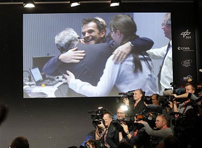 Celebrating scientists in the main control room appear on a video screen at the European Space Agency after the first unmanned spacecraft Philae landed on a comet called 67P/Churyumov-Gerasimenko, in Darmstadt, Germany, Wednesday, Nov. 12, 2014. Europe's Rosetta space probe was launched in 2004 with the aim of studying the comet and learning more about the origins of the universe. (AP Photo/Michael Probst)