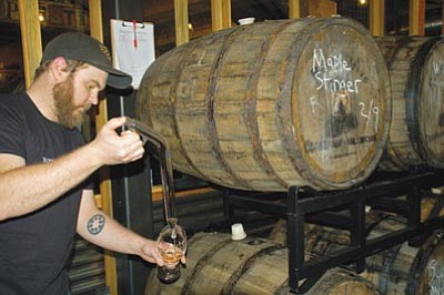 Cindy Barks/The Daily Courier<br>Carlos Bassetti, mead maker at Superstition Meadery, takes a sample from a barrel on display in the business, which is located in the basement level of the historic Burmister building on Gurley Street.