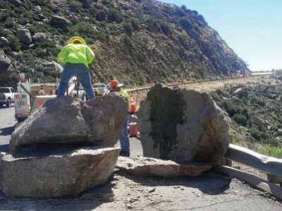 ADOT/Courtesy photo<br>A Department of Transportation crew works to break up a 20-ton boulder Wednesday that rolled onto Highway 89 south of Yarnell March 2. ADOT officials said heavy rains from a powerful storm dislodged it from the mountainside above.