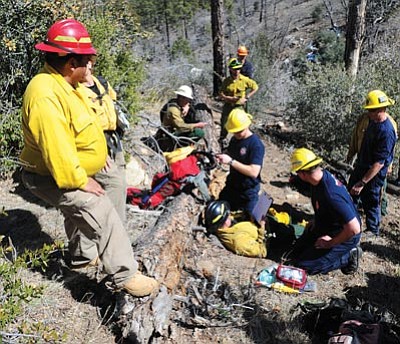 Les Stukenberg/The Daily Courier<br>Top picture, class members do a victim assessment as the Arizona Wildfire Academy Fire Line Medical Provider class goes to Thumb Butte for field day on simulated remote rescue Monday.  Class members, bottom, carry the victim up the mountainside.