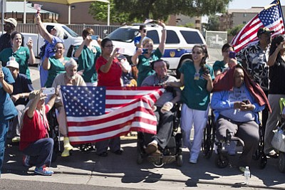 People hold flags as President Barack Obama's motorcade passes by en route to the Phoenix VA Medical Center Friday, March 13, 2015, where he will attend a meeting on veterans issues. (AP Photo/Jacquelyn Martin)