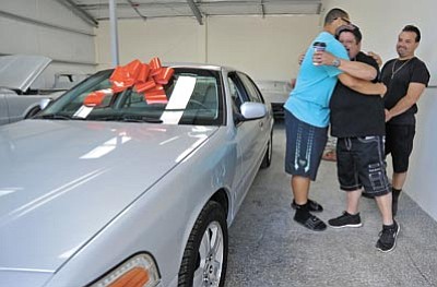 Louie Gomez, co-owner of Prescott Tire Pros & Automotive Service, gets a big hug from DJ Davidson, while fellow co-owner Jayme Salazar looks on after the owners gave Davidson a 2003 Crown Victoria they repaired Saturday afternoon in Prescott.  Davidson plans to use the car to travel to and from summer school and football practice.(Matt Hinshaw/The Daily Courier)