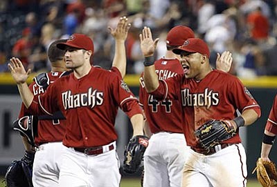 Ross D. Franklin/The Associated Press<br>Yasmany Tomas, right, celebrates with teammates A.J. Pollock, left, Paul Goldschmidt, back right, and Welington Castillo after the D-backs’ win Wednesday night in Phoenix.