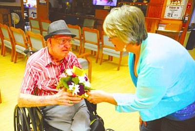 Les Stukenberg/The Daily Courier<br>Rakini Chinery hands out flowers to Ward Roberts at the Arizona Pioneer’s Home in Prescott Tuesday morning. Allan’s Flowers and More handed out more than 500 bouquets to residents of the Prescott VA, Alta Vista Retirement Home as well as the Arizona Pioneer’s Home.