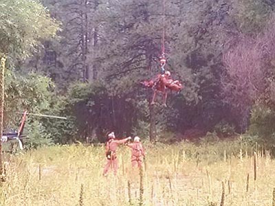 YCSO/Courtesy photo<br>
A hiker and a member of the Yavapai County Sheriff’s Office back country team are lowered to the boat launch area of Granite Basin Lake on Monday near Prescott. The rescue was applauded by a large crowd that had gathered nearby.
