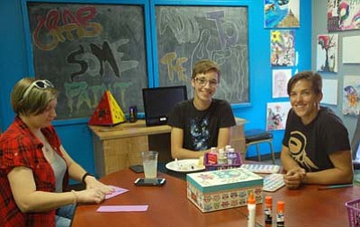 The Launch Pad Teen Center opened in the former Prescott Adult Center building on Aubrey Street and includes a reading room, music room, and this arts and crafts room where Bryanna Allen, 18, left, works on an origami project, and Alex DuBroy, 17, center, and Launch Pad Director Courtney Osterfelt visit together at the Sept. 17 open house. (Sue Tone/The Daily Courier)