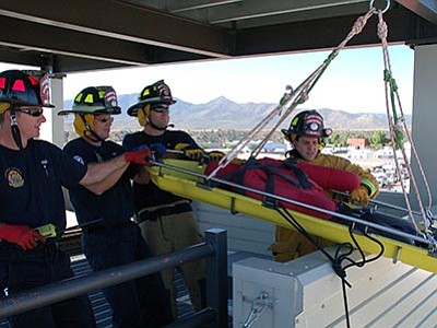 The crew of Engine 53, from left, Capt. Travis Smith, engineer Jim Bushman, and firefighter Kellan Eckle, are joined by trainee Kyle Runo in working a rescue scenario where they must deliver a patient from a fifth-floor landing.