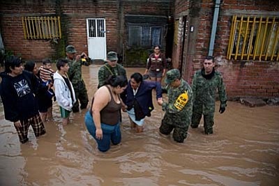 Soldiers help a woman to leave her flooded house to take her to a shelter in Zoatlan, Nayarit state, some 150 km northwest of Guadalajara, Mexico, Saturday, Oct. 24, 2015. Hurricane Patricia made landfall Friday on a sparsely populated stretch of Mexico's Pacific coast as a Category 5 storm, avoiding direct hits on the resort city of Puerto Vallarta and major port city of Manzanillo as it weakened to tropical storm force while dumping torrential rains that authorities warned could cause deadly floods and mudslides. (AP Photo/Eduardo Verdugo)