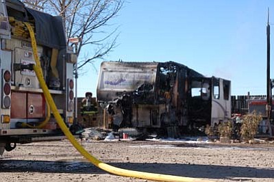 The frame of a fifth-wheel trailer at Paulden RV Park still smolders as firefighters inspect damage early Monday afternoon. Fire crews had responded to the same trailer earlier in the day, and the cause of the second fire remains under investigation. (Les Bowen/The Daily Courier)