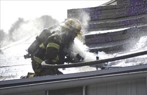 Prescott firefighter Aaron Laipple tries to cool hot spots during a fire on the roof of an apartment building on North Willow Street in Prescott Thursday.

Courier/Les Stukenberg