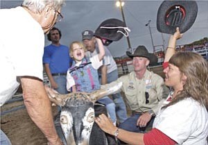 Courier/Nathaniel Kastelic
Gracie Woodard, 6, waves her hat and rides the bull at the Horses with H.E.A.R.T Happy Hearts Rodeo at the Prescott Rodeo Grounds Thursday night.