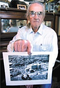 Courier/Nathaniel Kastelic
Herm Federwisch poses with an exterior photograph of the location where the U.S. Atomic Energy Commission conducted their Atomics International Sodium Reactor Experiment, which is in the Santa Susana Mountains in California, at his Chino Valley home Sunday.