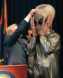 The Associated Press/Scott Troyanos --- 
Arizona Gov. Fife Symington pulls a mask off of aide Jay Heiler, dressed up as an alien, during a late afternoon news conference at the state capitol in downtown Phoenix Thursday June 19, 1997.  Symington, earlier in the day, said he would order the Arizona Department of Public Safety to look into the mysterious lights seen over Phoenix, but later insisted he was joking. 
