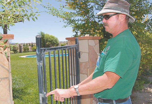 The Daily Courier/Doug Cook
<br>
Town of Chino Valley code enforcement officer Michael Bovee shows a good example of a safe backyard pool gate that latches and releases properly. CV homeowner Jerry Carpenter installed the fence three years ago at his residence on the corner of Road 4 North and Maricopa Street.