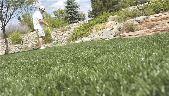 Gary Hollenbeck maintains his new monofilament polypropylene synthetic turf in his Prescott backyard Wednesday.